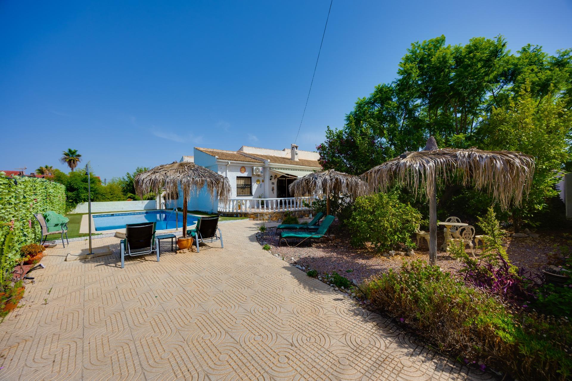 Covered patio with outdoor seating beside pool, 4-bedroom villa, La Siesta